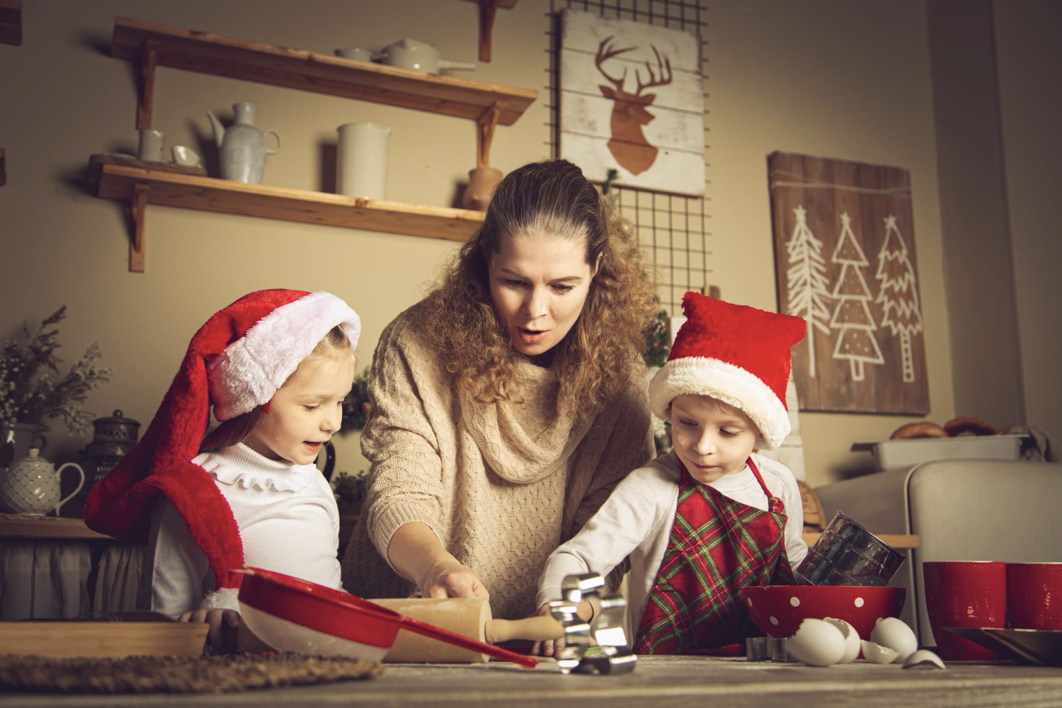 Jeune maman qui fait des activités de noël avec ses enfants dans une cuisine